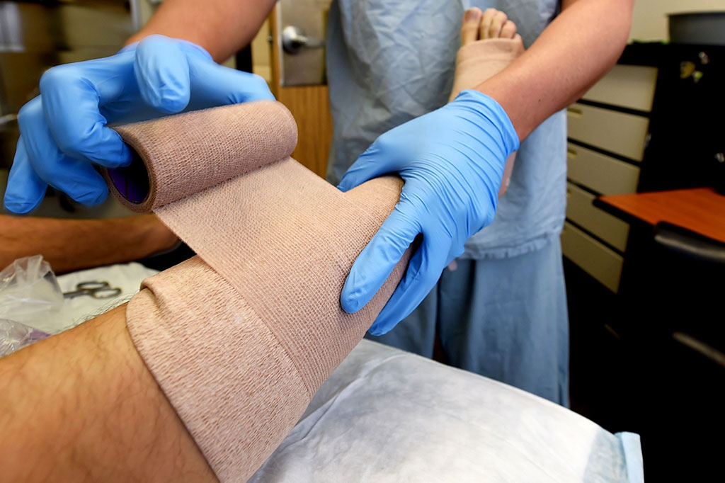 A nurse applying a bandage to a patients leg.